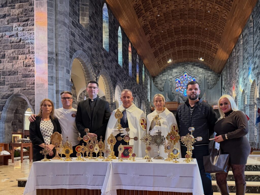 A group of people stand behind a table displaying several golden reliquaries inside a stone church.